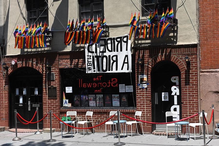 Stonewall building with a sign that reads "Pride's a Riot" 