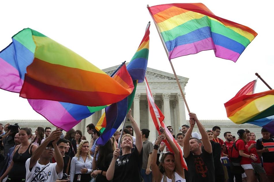 人们在美国国旗前挥舞着彩虹旗.S. Supreme Court